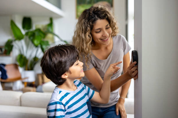 mother and son at home using a smart thermostat - energiebesparing fotos stockfoto's en -beelden