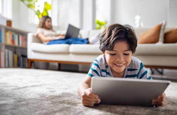 istock Boy watching videos on a digital tablet while his mother is working on her laptop 1678741982