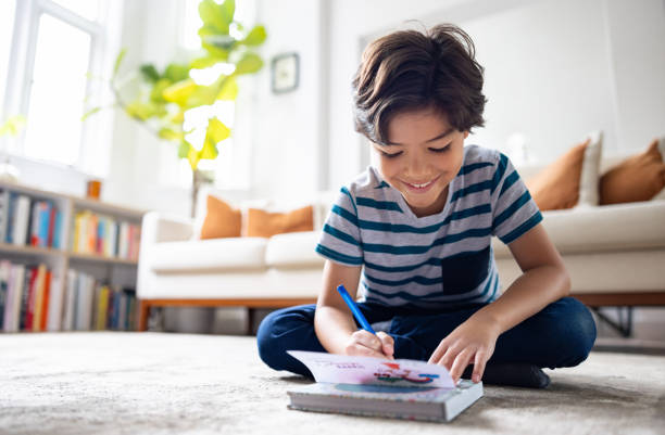 Happy boy coloring a book at home
