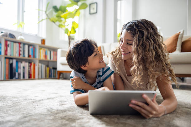 istock Happy mother and son using a digital tablet while relaxing at home 1678742497