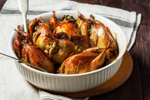 istock Baked quail stuffed with mushrooms, eggs and bread in a ceramic form on a wooden table. 1678768328