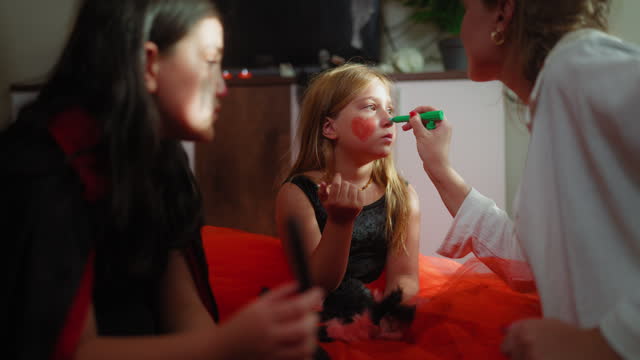 Young woman painting children’s faces during house Halloween party