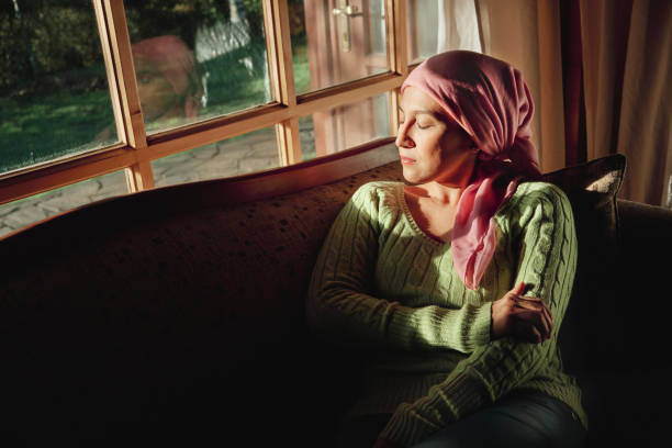 kobieta chora na raka siedzi w ciemnym pokoju na kanapie z zamkniętymi oczami - chusta zdjęcia i obrazy z banku zdjęć