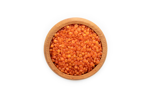 Red lentils in a wooden bowl isolated on a white background