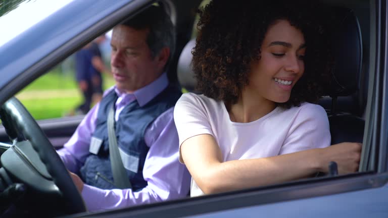 Beautiful black woman fastening her seat belt ready for her driving lesson with a male instructor