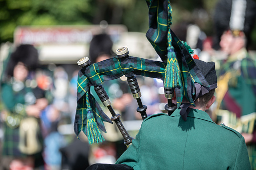 Scottish festival with the back of a bag piper playing with a larger band - Scotch Pipers.