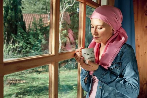 Cancer survivor rests near the window while drinking a cup of tea