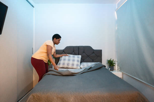Mature woman arranging the bed in the bedroom at home