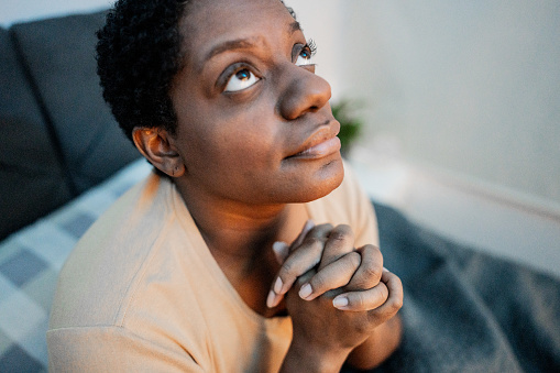 Mature woman praying in the bedroom at home