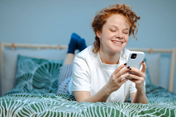 istock Young woman in pajamas using smart phone in bed 1678878026