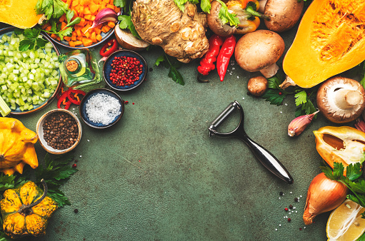 Autumn food. Pumpkin, mushrooms, roots and vegetable peeler. Ingredients for vegan, vegetarian cooking. Fall harvest. Healthy diet eating, slow food concept. Rustic green table background, top view