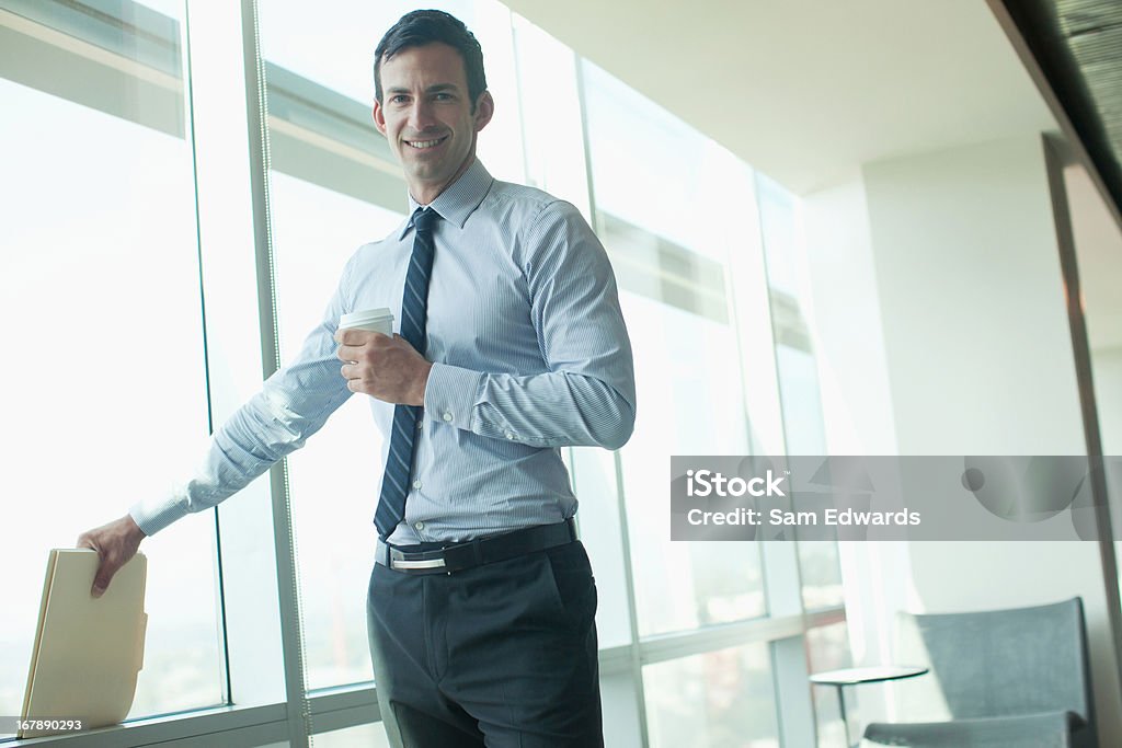 Hombre de negocios de pie en la ventana en oficina - Foto de stock de 30-34 años libre de derechos