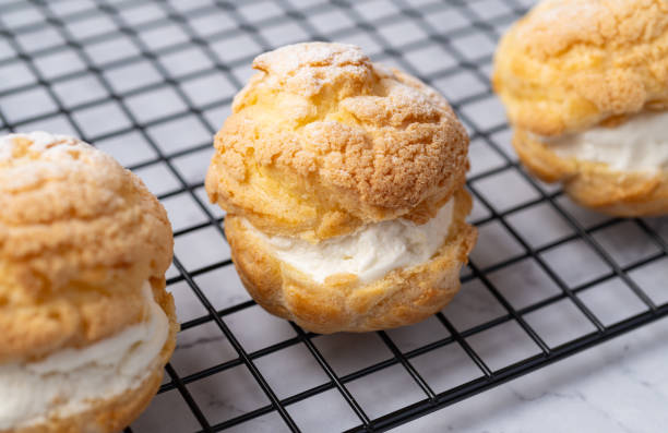istock Choux cream, vanilla whipped cream stuffed cake over metal grid 1678918412