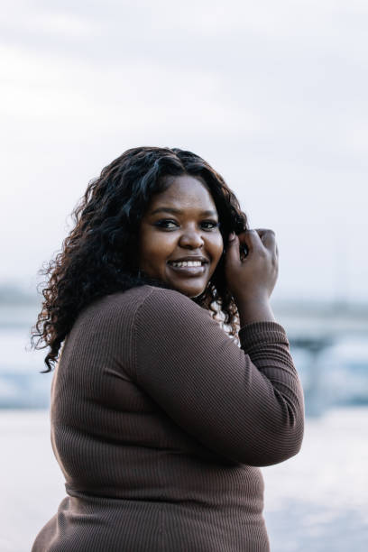 istock Vertical confident black-haired Afro-American plump woman look camera, posing duck lips against blue sky. Body positive 1678933037