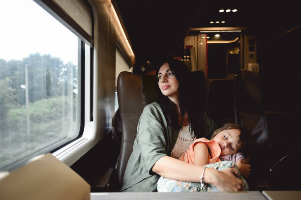 istock Affectionate mother embracing sleeping daughter while traveling by train. 1678950417