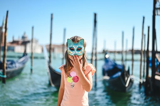 Venice, Italy - February 21, 2022: The Carnival of Venice, when visitors and residents of Venice dress up in wonderfully elaborate costumes and parade through the squares and along the banks of the canals. Here we see once such celebrant in a spectacular gold and green outfit.