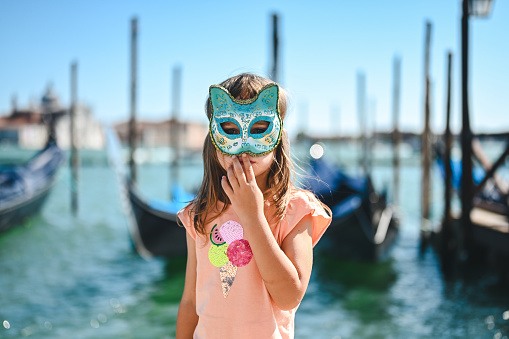 little girl in a Carnaval mask in Venice in front of Grand canal.