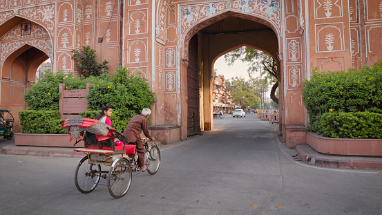 Indian man riding his bicycle rickshaw with a female customer near famous Ajmeri Gate, Jaipur, Rajasthan, India.