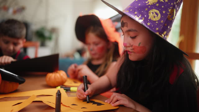 Small children friends making Halloween decorations during house Halloween party gathering