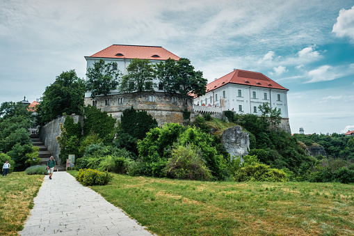 People walk below Veszprem Castle in Veszprem, Hungary on a cloudy day.