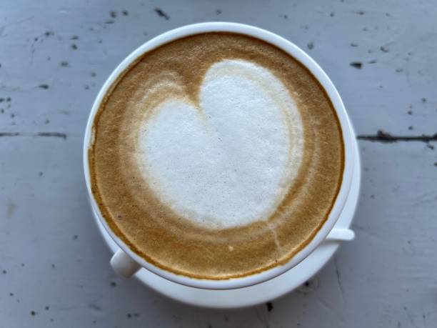 istock A cup of coffee with heart pattern in a white cup on wooden background. 1679010898