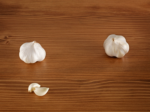 Organic garlic gloves on wooden background.