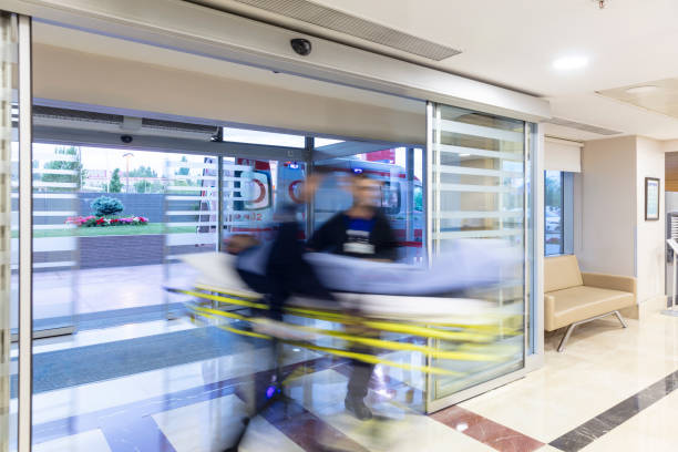 The paramedics take the patient from the ambulance to the hospital on a stretcher. The paramedics take the patient from the ambulance to the hospital on a stretcher. Two paramedics and a patient. Modern ambulance. Emergency room entrance of a large hospital. hospital emergency sign stock pictures, royalty-free photos & images
