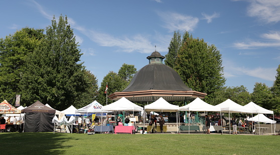 Maple Ridge, Canada - July 15, 2023: Vendors at the popular Haney Farmers Market prepare their stalls near the bandstand in Memorial Peace Park downtown. Summer morning with light clouds over Metro Vancouver, British Columbia.