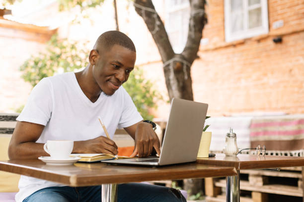 istock Serious, concentrated and enthusiastic afro american man using laptop and drinking coffee in internet cafe. Do business 1679124340