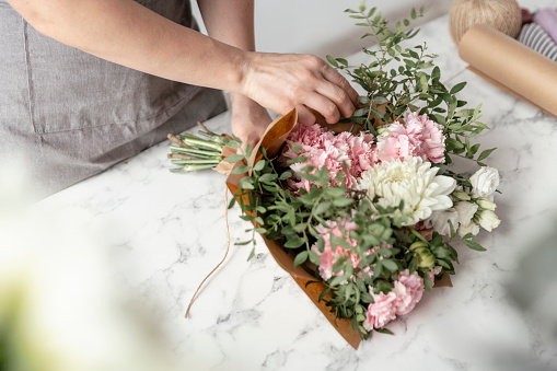Woman making bouquet with beautiful jasmine flowers in kitchen, closeup