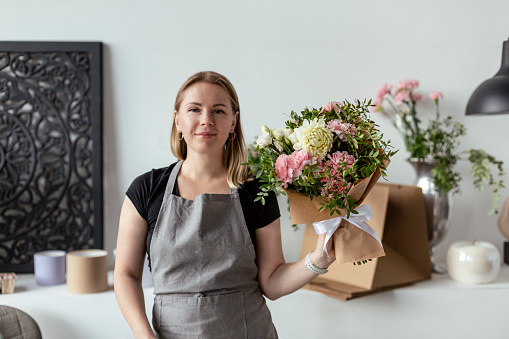 An employee of a flower boutique holds a freshly picked bouquet