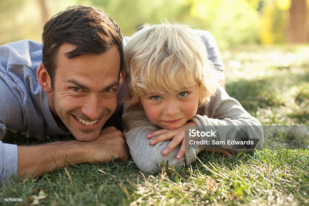 Padre e hijo sentar en hierba juntos - Foto de stock de 30-34 años libre de derechos