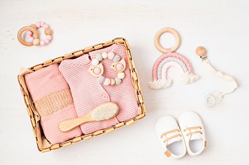 Gift basket with gender neutral baby garment and accessories. Care box of organic newborn booties, fashion, branding, small business idea. Flat lay, top view