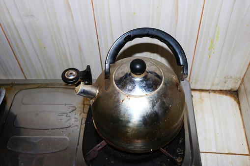 Vintage large aluminum tea pot kettle stove top isolated on the stove with the fire not on after boiling the water