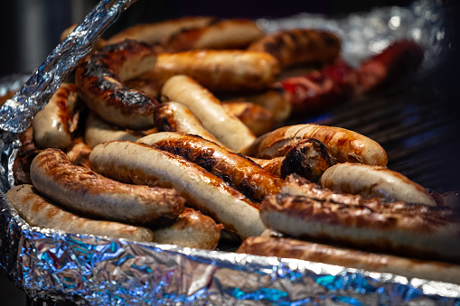Picture of a batch of bratwurst sausages cooking in a fast food in Germany. Bratwurst is a type of German sausage made from pork or, less commonly, beef or veal. The name is derived from the Old High German Brätwurst, from brät-, finely chopped meat, and Wurst, sausage, although in modern German it is often associated with the verb braten, to pan fry or roast.