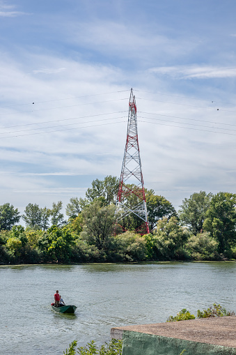 Picture of a fishermen oat on the danube river in fornt of an electrical pylon in Banatska Palanka, in Serbia.