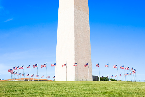 Bottom of the Washington Monument in Washington DC, United States with flags circling it.