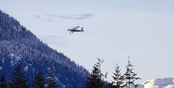 Small Airplane flying around Canadian Mountain Landscape. Squamish, BC, Canada.