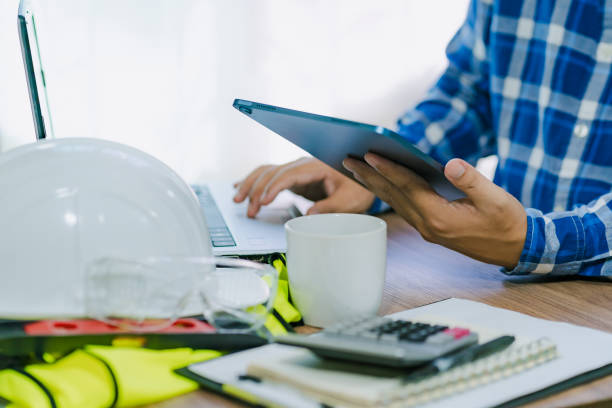 istock Close-up of an architect or engineer's hand holding a tablet to be creative in project design and drafting in the office and calculate the construction budget estimate on the work desk 1679401696