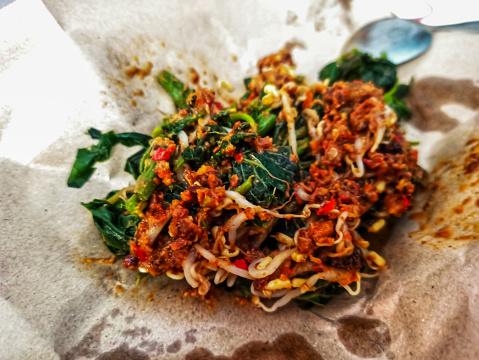 Discover the delicious world of Pecel, a peanut sauce vegetable dish, artfully encased in an oil paper wrap. This photo captures the essence of Indonesian cuisine.