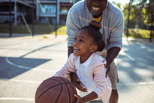 Close up of a Grandfather and granddaughter playing basketball together on an outdoors basketball court