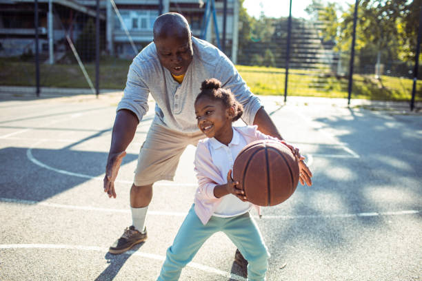 dziadek i wnuczka grają razem w koszykówkę na odkrytym boisku do koszykówki - czarni zdjęcia i obrazy z banku zdjęć
