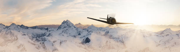 Military old airplane flying over the mountain peaks.
