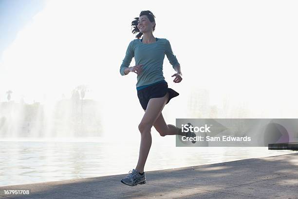 Donna Che Corre Lungo Il Lago Nel Parco - Fotografie stock e altre immagini di Correre - Correre, Donne, Solo una donna