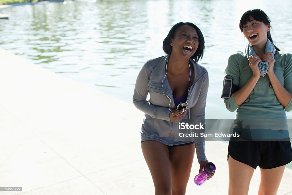 Mulheres caminhando juntos pelo lago no parque - Foto de stock de 25-30 Anos royalty-free