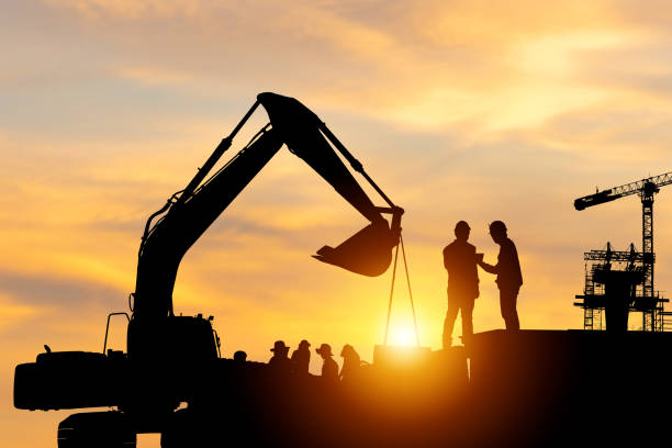 istock Silhouette of Engineer and worker checking project at building site background, construction site at sunset in evening time 1679548601
