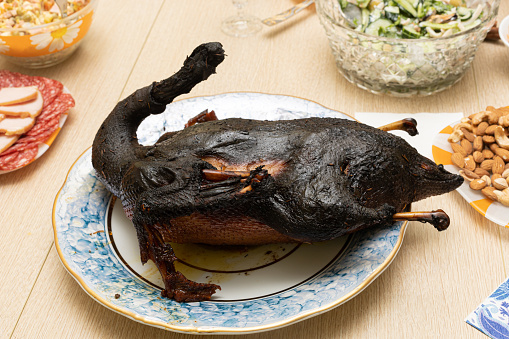 Burnt bird carcass on serving dining table. Serve charred spoiled dish. Lousy housewife and bad chef. Delicious cold starters and terrible main course. Disgusting cooking, ruined celebration.