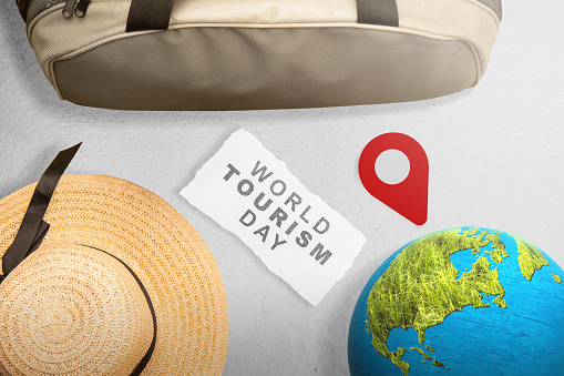 Hat and bag with a globe on gray background. World tourism day concept