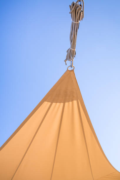 バルコニーまたはパティオの日当たりの良い青い空に対する日よけの帆または日よけの詳細 - shade sail awning textile ストックフォトと画像
