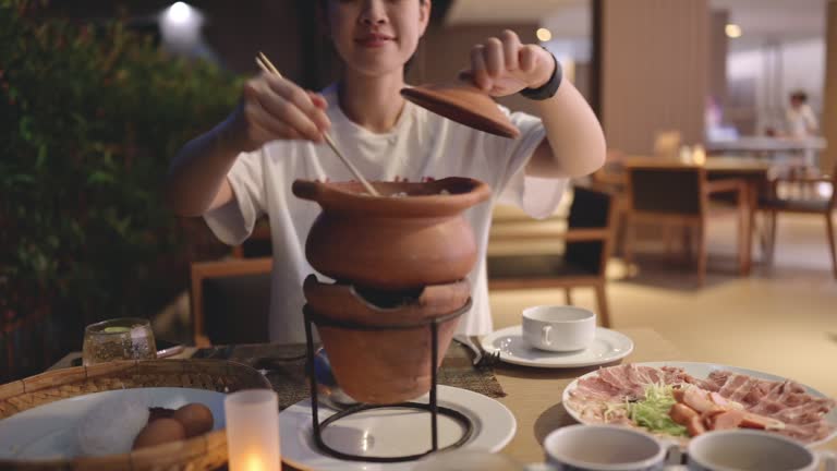 Asian adult preparing and enjoy traditional Chim chum thai hotpot spice meal dinner in luxury restaurant